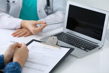  Close-up of a doctor and  patient  sitting at the desk while physician pointing into laptop computer. Medicine and health care concept