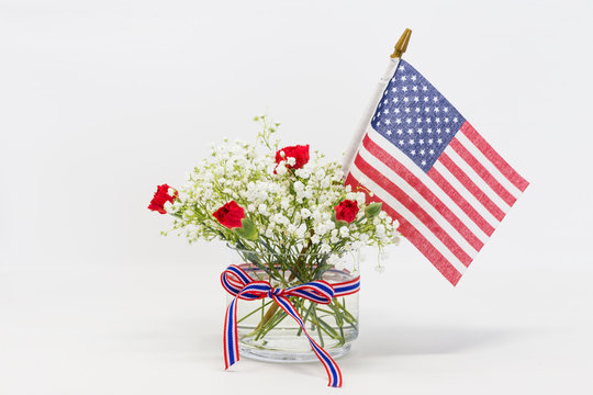 Red and white flower and US flag against white background, 