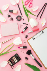 Composition with clipboard, flowers, cosmetics and accessory on pink background. Top view. Flat lay. Home feminine desk.