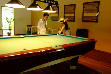 The couple playing snooker in the sport center.