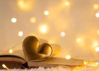 heart shape from paper of old book with warm LED light strip on wool