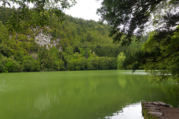 Fototapeta na wymiar Lake Congo on Sao Miguel Island, Azores, Portugal. Emerald color of lake waters surrounded by lush forest.