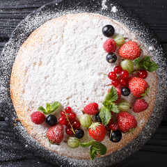 Victoria sandwich cake decorated with fresh summer berries and mint in the form of a wreath close-up. top view