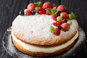 Victoria sandwich cake decorated with fresh summer berries and mint in the form of a wreath close-up. horizontal