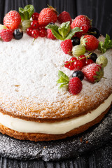Traditional Victoria sandwich cake with fresh berries and mint closeup. vertical