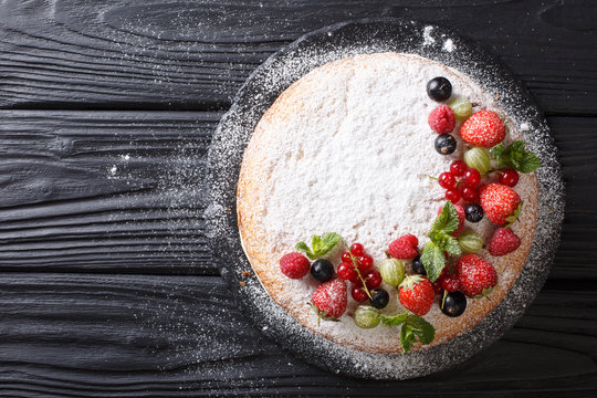 Beautiful dessert: Victoria sandwich cake decorated with fresh summer berries and mint closeup. Horizontal top view