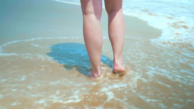 Legs feet caucasian girl walking barefoot wet sand island beach. Slow Motion. Close Up Shot. Colorful