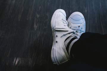 Fototapeta premium Man wearing white sneakers in black trousers sitting on coffee shop,Vintage tone.Selective focus