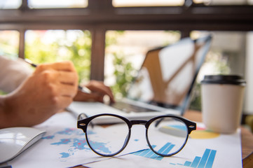 glasses and laptop on wooden desktop in modern office with accessories,Copy space for your text