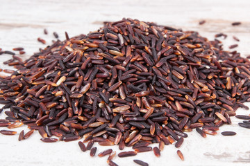 Heap of black rice on rustic board, healthy nutrition concept