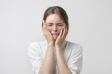 Woman in modern glasses covering ears and shouting.