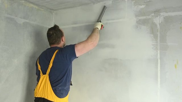 refurbishment. Worker spackling a wall with putty