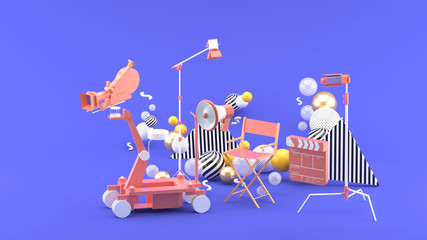 Movie camera, director chair,megaphone and movie clapper among colorful balls on a purple...