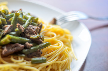 Large White Plate with Hot Delicious Pasta with Meat and Green Beans on a Glossy Table. Spaghetti Dish Background