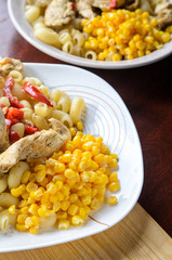 Hot Pasta with Chicken Breast Meat and Vegetables in Large White Plate on Wood Table, Close-Up. Food Background