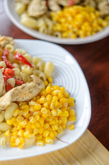 Hot Pasta with Chicken Breast Meat and Vegetables in Large White Plate on Wood Table, Close-Up. Food Background