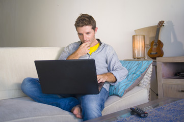 young attractive and successful man working from home living room sitting on couch networking on laptop computer happy in freelancer job