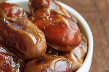 Khalas date palm on wood table in close up with copy space for background or wallpaper. Dates fruit is food for Ramadan or medjool. Delicious dried fruit with sweet taste and have high fiber.