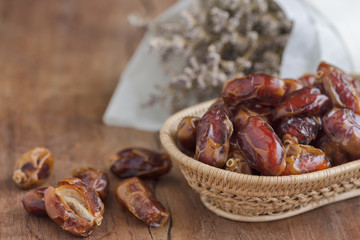 Khalas date palm on wooden basket in side view with copy space on wood table for background. Dates fruit is food for Ramadan or medjool. Delicious dried fruit with sweet taste and have high fiber.