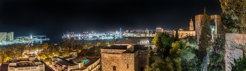 Extra wide panorama view of the Alcazaba castle, Cathedral, and the port of Malaga, Spain at night. Citiscape at night.