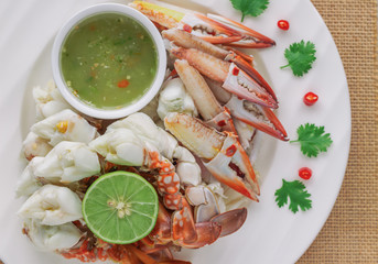 Steamed crab meat prepared for ready to eat with Thai style spicy dipping sauce on white plate in top view flat lay with copy space for background or wallpaper. Delicious homemade seafood concept.