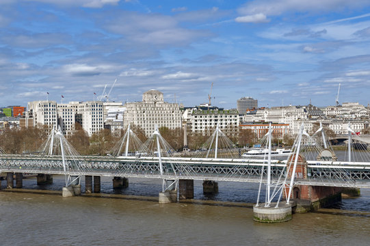 Aerial view of Hungerford Bridge, a steel truss railway bridge, flanked by the Golden Jubilee Bridges, two cable-stayed pedestrian bridges over the River Thames in London, England, UK