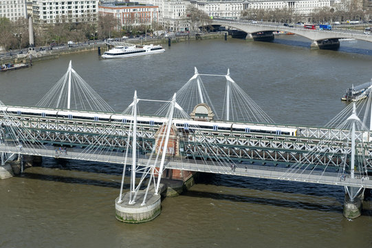 Aerial view of Hungerford Bridge, a steel truss railway bridge, flanked by the Golden Jubilee Bridges, two cable-stayed pedestrian bridges over the River Thames in London, England, UK