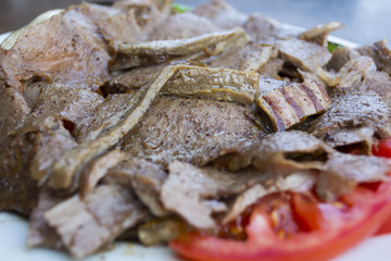 turkish iskender kebab with garnish on a wooden surface at restaurant.