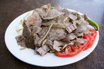 turkish iskender kebab with garnish on a wooden surface at restaurant.