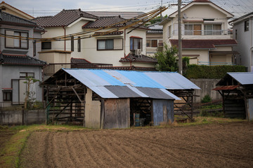 Fototapeta na wymiar Farming shack in Japanese neighborhood with field prepared for planting