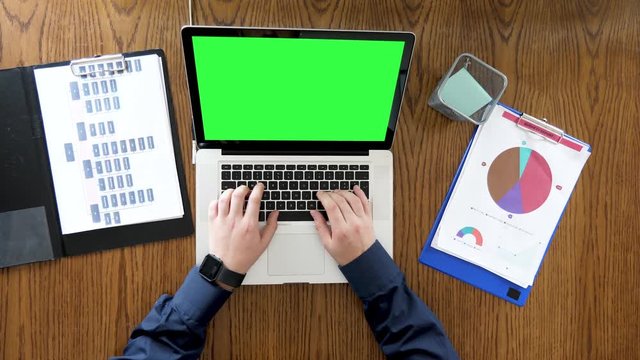 Businessman hands scrolling and typing on a laptop with chroma green screen. Top view footage