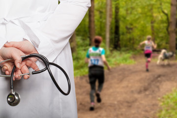 The doctor put his hands with stethoscope behind his back on a blurred background