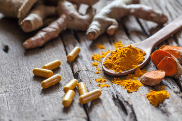 Turmeric powder, turmeric capsule and turmeric on wooden background