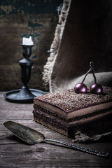 Homemade cherry cake with chocolate decor on a rustic style background. Selective focus. Toned