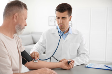 Fototapeta premium Doctor measuring patient's blood pressure in hospital