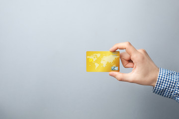 Young man holding credit card on grey background