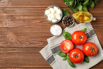 Flat lay composition with tomatoes, mozzarella cheese balls and basil on wooden background