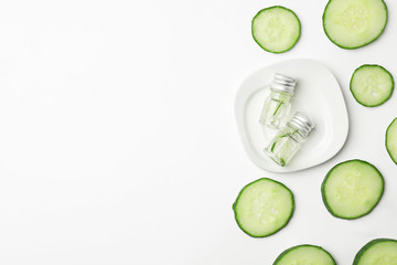 Flat lay composition with fresh cucumber skin care tonic and bottles on white background