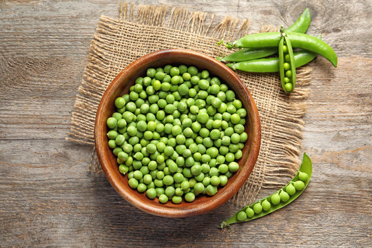 Flat lay composition with green peas on wooden background