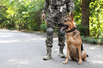 Man in military uniform with German shepherd dog outdoors
