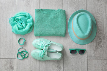 Flat lay composition with set of mint clothes and accessories on wooden background
