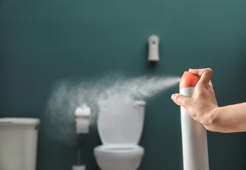 Woman spraying air freshener in bathroom - obrazy, fototapety, plakaty