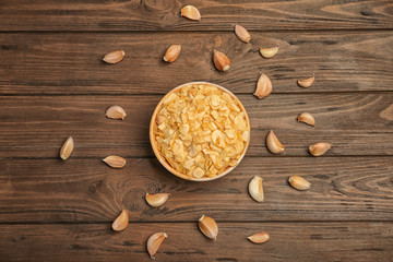 Fototapeta na wymiar Cloves and bowl with dried garlic flakes on wooden background, top view