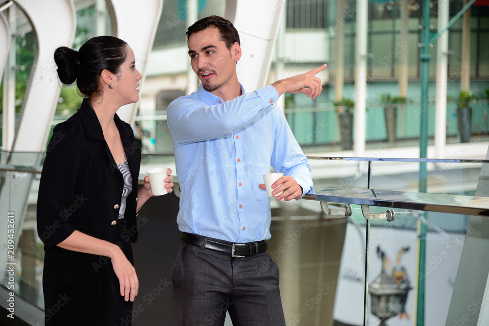 Wall mural businessman and business woman stand and talk about business plan with Plastic Mug on hand