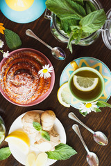 Cup of herbal tea with lemon and mint leaves, ginger root and baked good