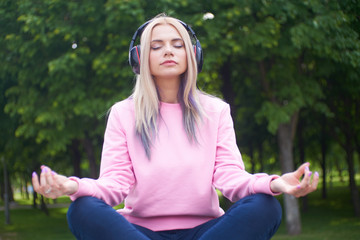 Beautiful girl in a park meditating. Do not be distracted by the external noise in the headphones....