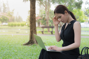 businesswoman sit in the park and her hand clasped head, the feeling of stressed, sadness or displeasure caused by business failure.