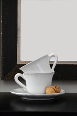 Tea cups on a table against a white sheet background in a frame.
