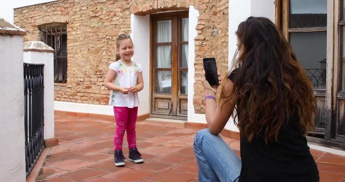 mother woman with mobile smartphone shooting video four years age blonde child in a roof of house
