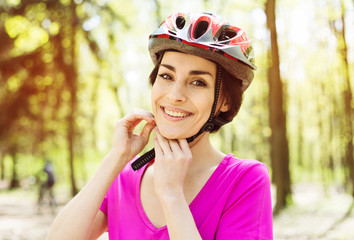 Bike helmet. Woman Putting Biking Helmet on Outside During Bicycle Ride.